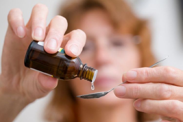 Mujer vertiendo el medicamento en una cuchara