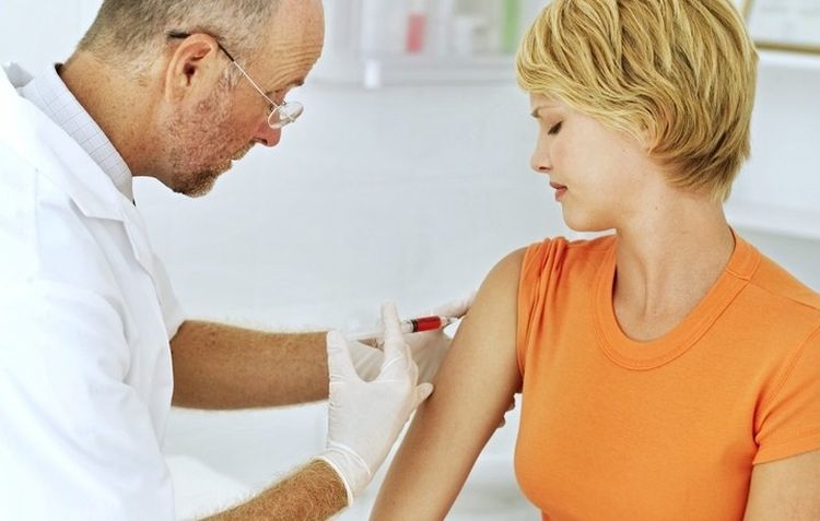 El doctor administra una inyección en el hombro.